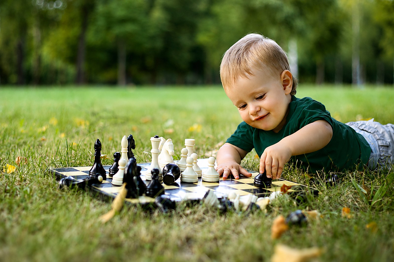 A child playing chess on the grass in a park