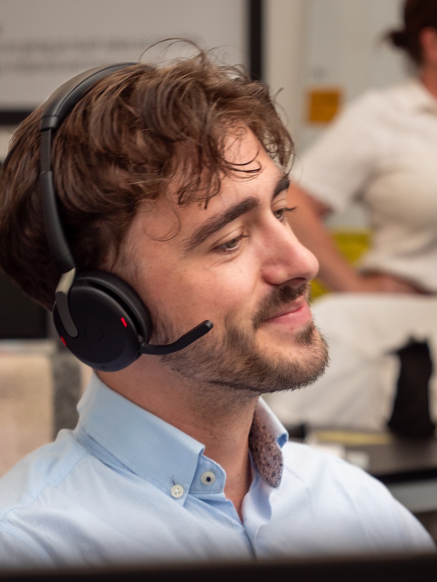 Alex P of Aspire Estates, smiling at his desk wearing a headset