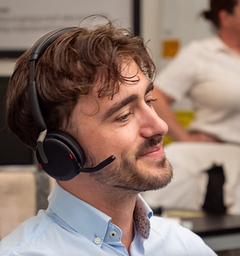 Alex P of Aspire Estates, smiling at his desk wearing a headset